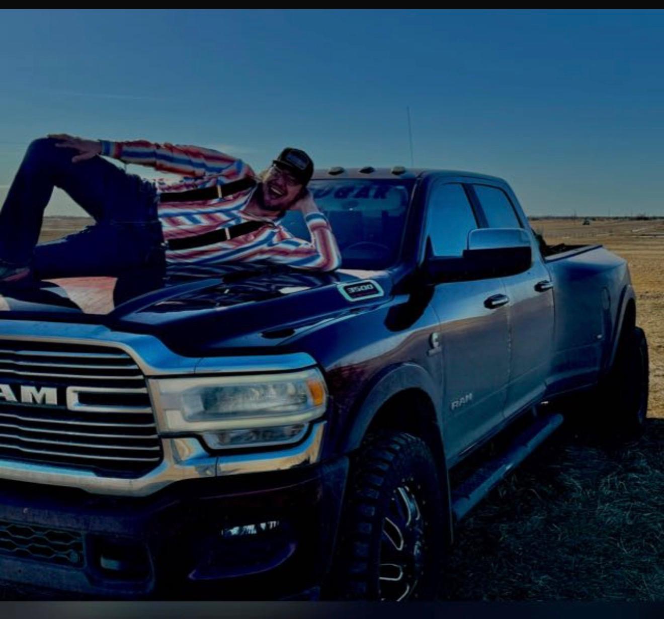 Steve Saddleback relaxing on the hood of his Ram truck on the prairie
